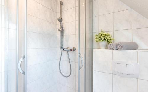 a shower in a bathroom with white tiles at Traumblick 2 mit Meerblick nach Amrum in Utersum