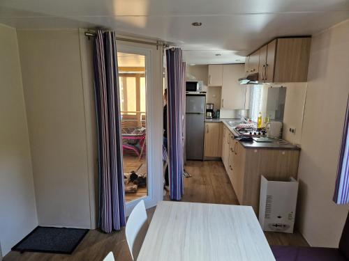 une cuisine avec une table au milieu dans l'établissement Mobil-home 40, à Samoëns