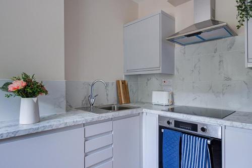 a white kitchen with a sink and a stove at Stay @ London Road Derby in Derby