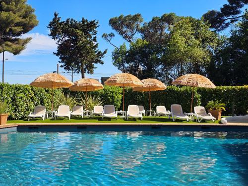 un grupo de sillas y sombrillas junto a una piscina en Luxotel Cannes, en Cannes