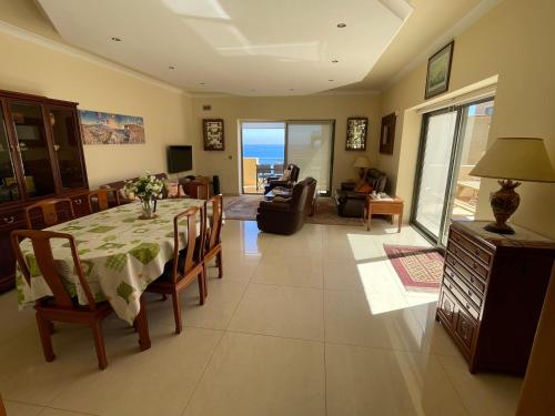 a living room with a dining room table with a view of the ocean at Seaview Family Apartment, Pool, Easy Access to the Sea, Near Mellieħa Bay in Mellieħa