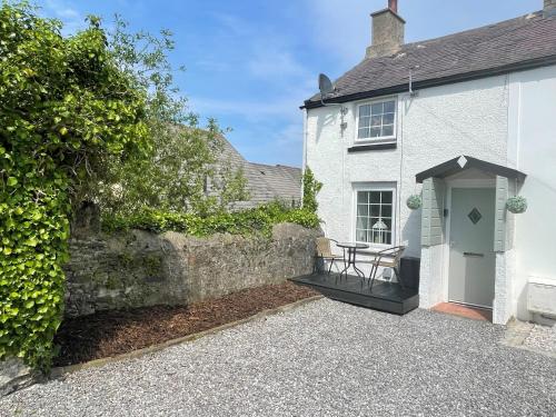 a white house with a table in front of it at Castle Wall Cottage in Conwy