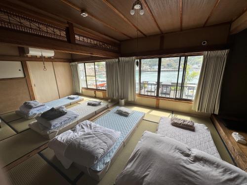 Habitación con 3 camas y ventanas. en すくもBOX, en Sukumo