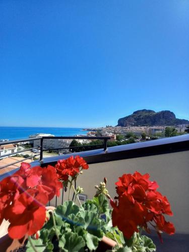 a view of the ocean from a balcony with red flowers at Holidays Cefalù in Cefalù