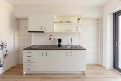 a kitchen with white cabinets and a sink at Apartma Lajf in Brežice