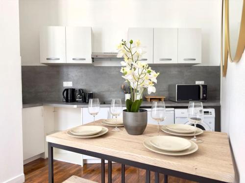 - une table à manger avec des assiettes et des verres à vin dans l'établissement Appartement Mezzanine Cosy 4P Champs elysées, à Paris