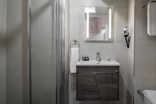 a white bathroom with a sink and a shower at İstanbul Efes Hotel in Istanbul