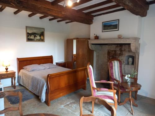 a bedroom with a bed and chairs and a fireplace at Maison studio village médiéval in Mont-Saint-Jean