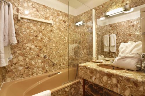 a bathroom with a tub and a sink at Hotel Amélie in Brides-les-Bains