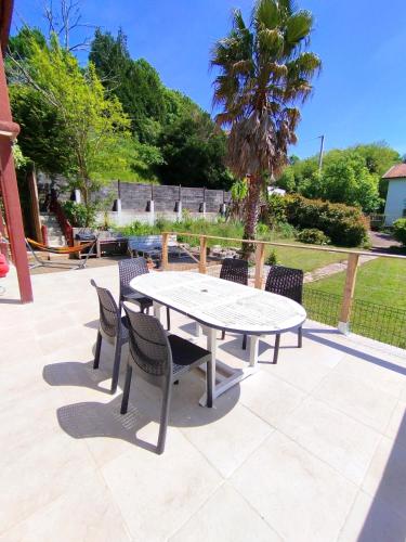 une table et des chaises sur une terrasse avec un palmier dans l'établissement Maison basque à 8 minutes des plages, à Ahetze