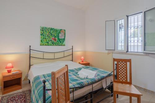 ein Schlafzimmer mit einem Bett, zwei Tischen und zwei Fenstern in der Unterkunft Villa Rosa con accesso sul mare in Pachino