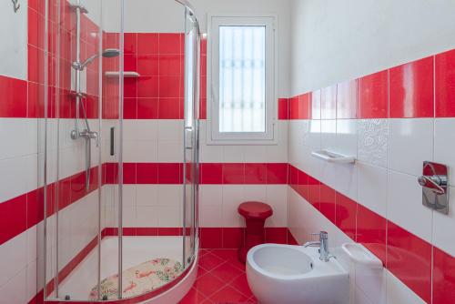 ein rot-weißes Bad mit einem Waschbecken und einer Dusche in der Unterkunft Villa Rosa con accesso sul mare in Pachino