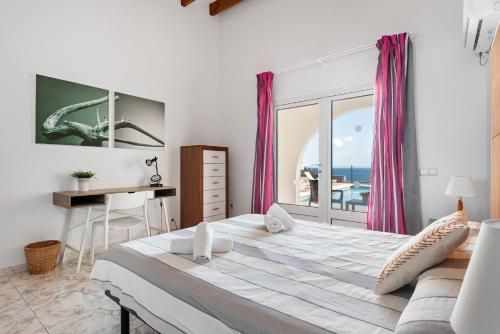a bedroom with a large bed and a desk and a window at Villa Panorama in Cala'n Porter