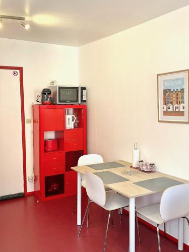 une salle à manger avec une table, des chaises et une armoire rouge dans l'établissement Studio Le cheval de Mers au coeur du centre équestre, à Mers-les-Bains