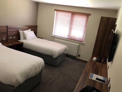 Habitación de hotel con 2 camas y ventana en Rivington Lodge en Bolton