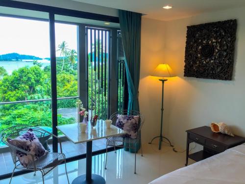 a room with a bed and a table and a window at Seaview At Cape Panwa in Panwa Beach