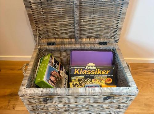 a basket filled with games and books on a floor at Ferienhaus Deine Zeit mit SAUNA und WALLBOX in Nettersheim