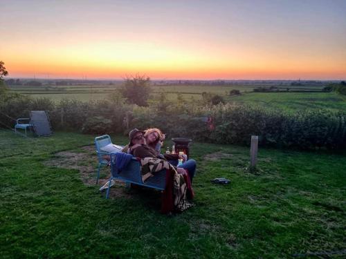 two people sitting in chairs in a field at sunset at Japanese tent Secret garden glamping in Newark upon Trent