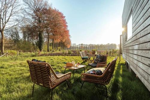 a group of chairs and a table in the grass at Tiny House Natuur & cultuur nabij Brugge! in Beernem