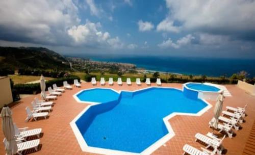 una gran piscina con tumbonas y el océano en Marasusa Apartments Scirocco en Parghelia
