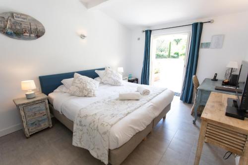 a bedroom with a bed and a desk and a window at Hotel Le Verger Maelvi in Grimaud
