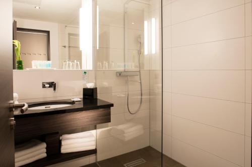 uma casa de banho com uma cabina de duche em vidro e um lavatório. em Vital Hotel Frankfurt em Hofheim