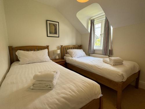 due letti singoli in una stanza con finestra di Primrose Cottage - South facing cottage in the heart of Dittisham a Dittisham