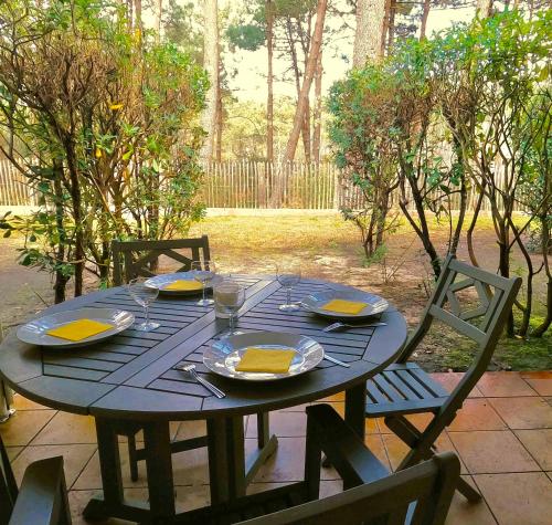 ein schwarzer Tisch mit Tellern und Servietten darauf in der Unterkunft Au milieu des pins, charmant appartement de 38 m2 - 4 personnes - Domaine du Golf in Lacanau-Océan