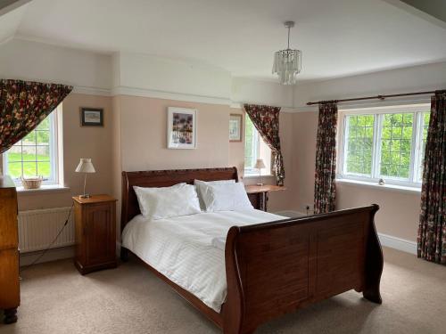 a bedroom with a large bed and two windows at Victorian cottage overlooking the Plym Valley in Bickleigh