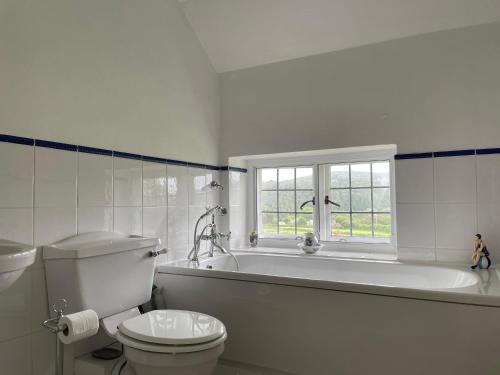 a white bathroom with a tub and a toilet at Victorian cottage overlooking the Plym Valley in Bickleigh