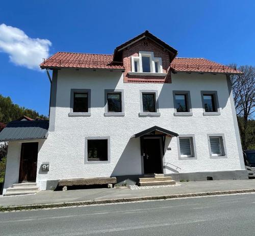 biały budynek z czerwonym dachem na ulicy w obiekcie Ferienhaus Linde w mieście Warmensteinach