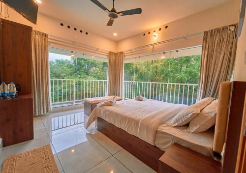 a bedroom with a bed and a large window at Glen Castle Vagamon Pool Resort by VOYE HOMES in Vagamon