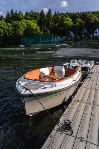 a boat is tied to a dock in the water at NOI Resort SPA - woda i las in Tęgoborze