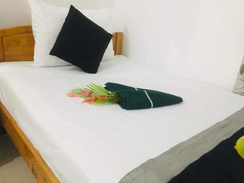 a white bed with black pillows and a green napkin at Nice Place Kandy in Kandy