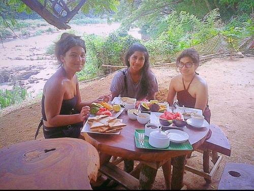 three women sitting at a picnic table with food at Nice Place Kandy in Kandy