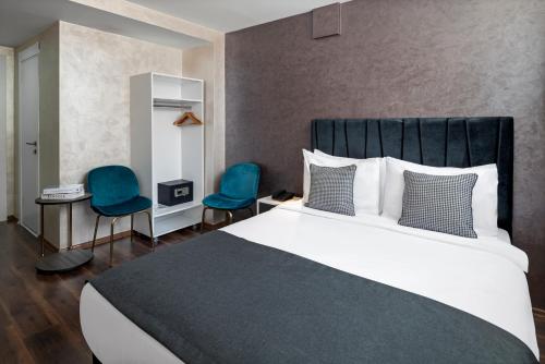 a bedroom with a large bed and two blue chairs at İstanbul Efes Hotel in Istanbul