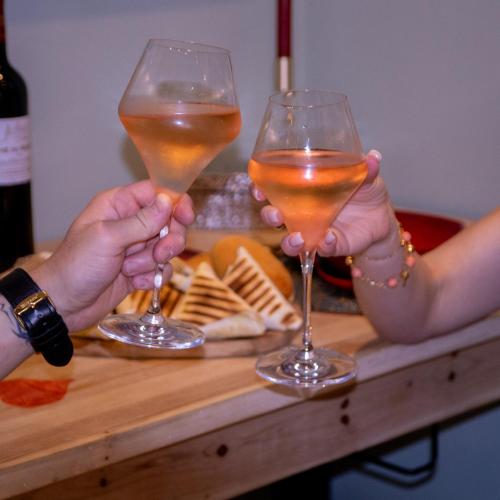 two people holding up wine glasses on a table at Évasion duo, Suite Atypique privative, Hammam & Balnéo in Auriol
