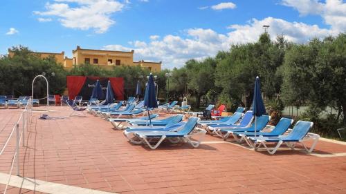 a row of lounge chairs with blue umbrellas at One bedroom apartement with shared pool terrace and wifi at Sciacca in Sciacca