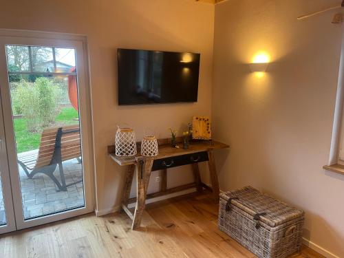 a room with a table and a television on the wall at Ferienhaus Deine Zeit mit SAUNA und WALLBOX in Nettersheim