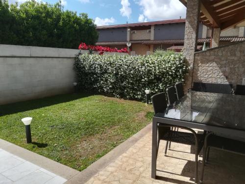 un tavolo e sedie in un cortile con una siepe di Alloggio Turistico Castel di Leva a Castel di Leva