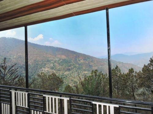 a balcony with two chairs and a view of mountains at Aurohill Homestay Chail in Shimla
