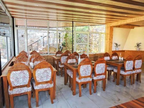 a dining room with chairs and tables and windows at Aurohill Homestay Chail in Shimla