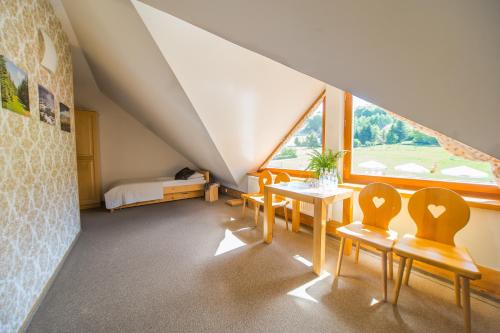 a attic room with a table and chairs and a bed at Olza Karczma i pokoje in Istebna