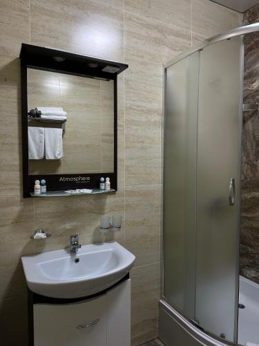 a bathroom with a sink and a shower and a mirror at Hotel Atmosphere in Poltava