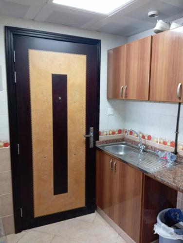 a wooden door in a kitchen with a sink at All in One in Sharjah