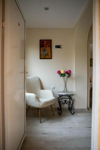 a room with a chair and a table with a vase of flowers at Avenue House in Kazanlŭk
