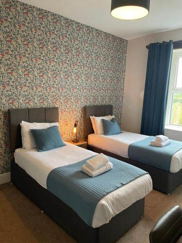 Duas camas num quarto com cortinas azuis e papel de parede em The Wheatsheaf Inn em Ingleton 