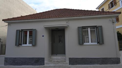 a small white house with a green door and windows at Vivis Hub in Argostoli