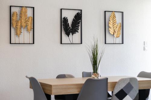 a dining room table with four framed feathers on the wall at Villa vue mer, terrasse et spa in Nice