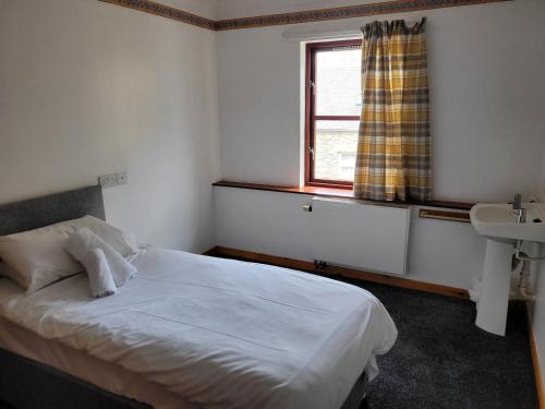 1 dormitorio con cama, ventana y lavamanos en Weston House Serviced Accommodation en Keith